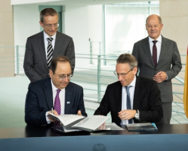 Keyvan Esfarjani, Intel's chief global operations officer, and Jörg Kukies, state secretary for Economic, Finance and European Affairs, sign the deal. Behind them are Intel chief executive Pat Gelsinger and German Chancellor Olaf Scholz.